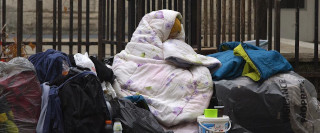 Une femme, sous une couverture, dans une rue de Paris.