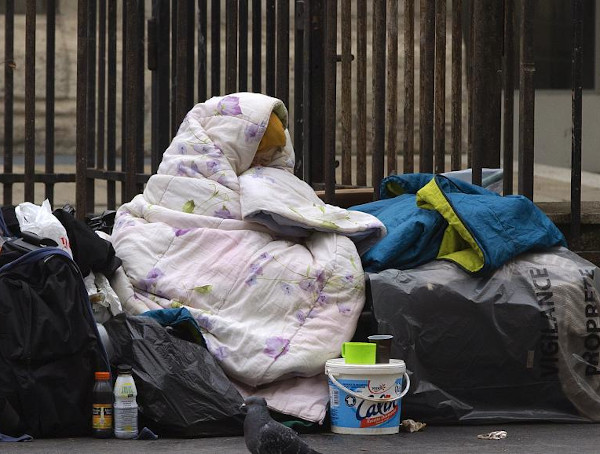 Une femme, sous une couverture, dans une rue de Paris.